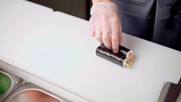 Male chef hands cutting prepared maki sushi roll on board in restaurant kitchen — Stock Video