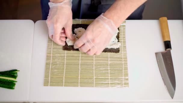 Mãos masculinas em luvas cozinhar rolos de sushi em uma cozinha restaurante de perto — Vídeo de Stock