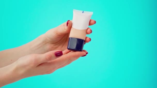 Vrouwelijke hand testen van de kleur van make-up foundation crème tegen blauwe achtergrond — Stockvideo