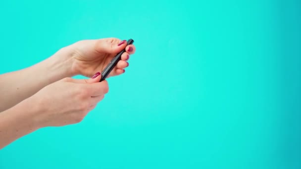 Female hands holding cosmetic eye liner pencils against blue background — Stock Video