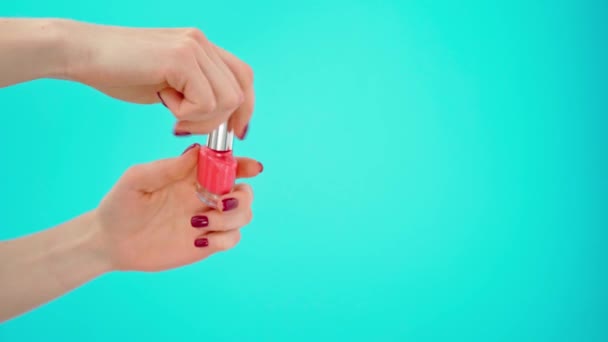 Main féminine tenant bouteille de vernis à ongles sur fond bleu — Video