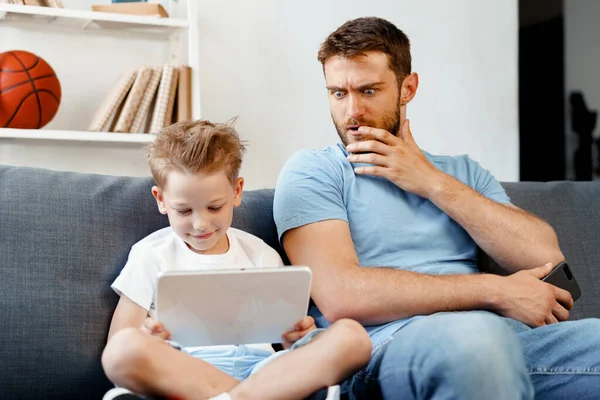 Bezorgde vader gluurt naar wat zijn zoon kijkt op digitale tablet — Stockfoto