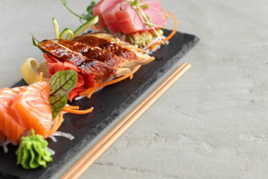 Somon, yılan balığı ve ton balıklı saşimi suşi tabakta servis edilir.