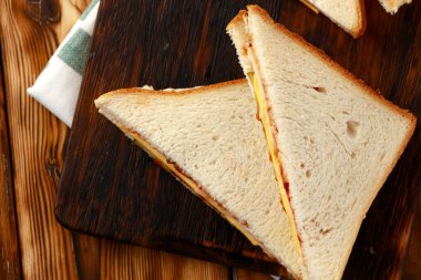 Tahta kesme tahtasında peçeteyle ikiye bölünmüş sandviçler.