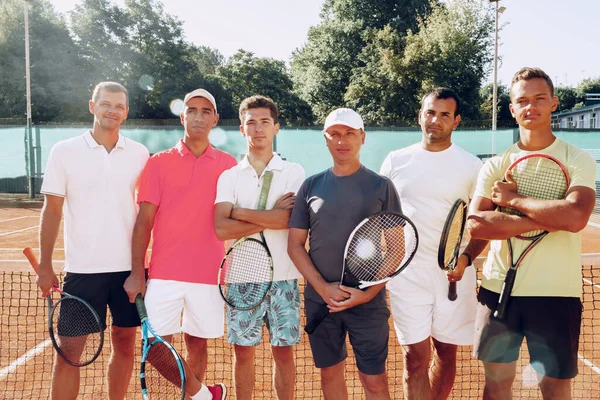 Group of six male tennis players standing on court