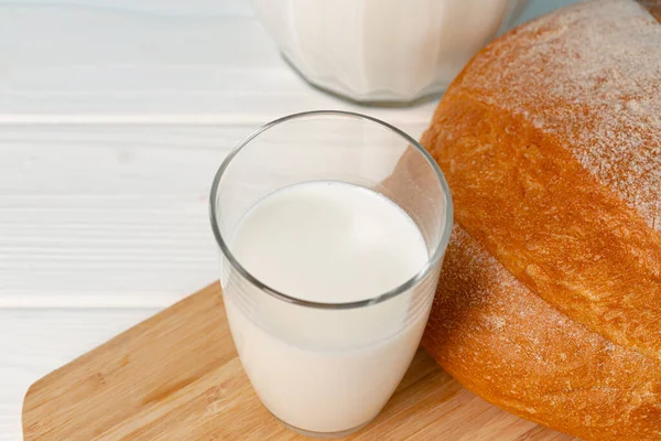 Чашка молока и хлеба на деревянном столе — стоковое фото