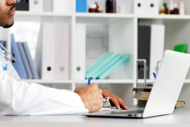 Doktorun elleri çalışma masasında otururken panoya bir şeyler yazıyor.