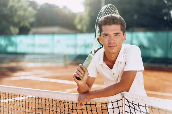 Young mixed race man tennis player with racket standing on tennis court