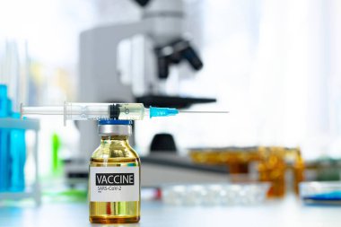 Laboratuvarın arka planına karşı enjeksiyon için küçük şişedeki aşı