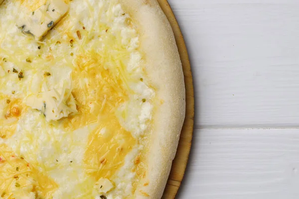 Pizza Dört peynir beyaz ahşap masada.
