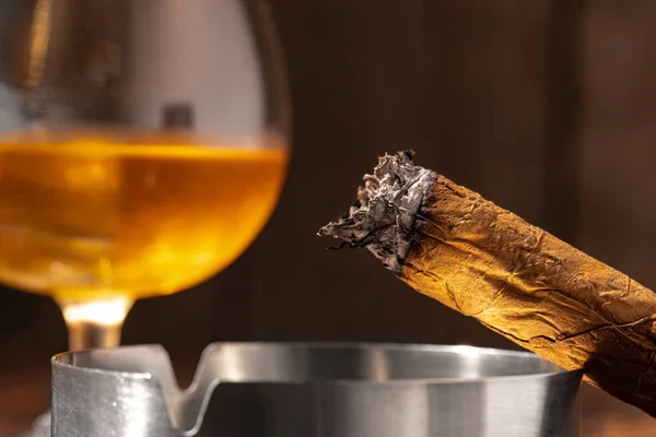 Vaso de whisky y cigarro encendido en un cenicero — Foto de Stock