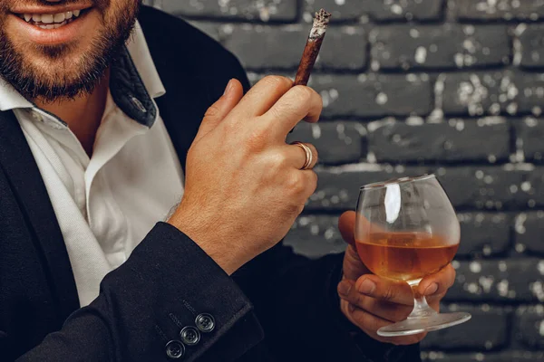 Hombre sosteniendo un vaso de whisky y cigarrillo encendido en las manos de cerca — Foto de Stock