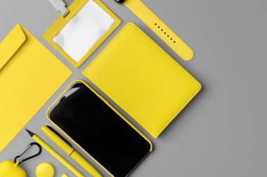 Akıllı telefon, akıllı seğirme ve gri arka planda kulaklık olan sarı not defteri.