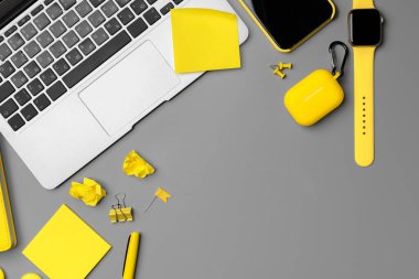 Akıllı telefon, akıllı seğirme ve gri arka planda kulaklık olan sarı not defteri.