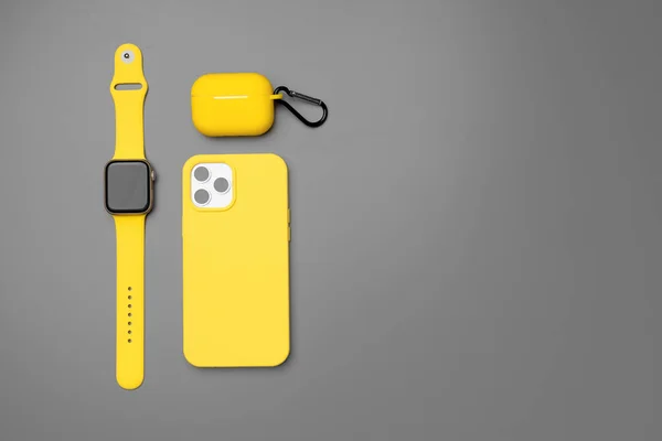 Smartphone jaune, smartwatch et écouteurs sur fond gris — Photo