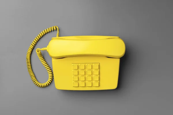 Amarelo. Telefone fixo no fundo cinza vista superior — Fotografia de Stock