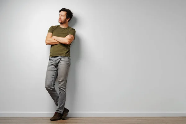 Portrait of a young casual man standing against grey background — Stock Photo, Image