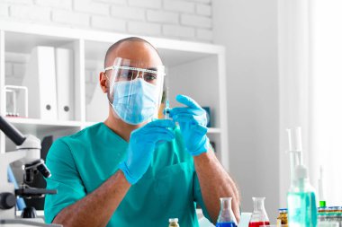 Afro-Amerikalı doktor masada oturuyor ve bir ilaç enjekte etmeye hazırlanıyor.