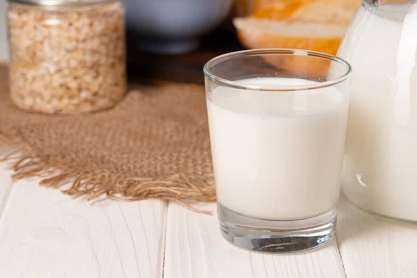 Glass of milk and oat flakes on wooden table