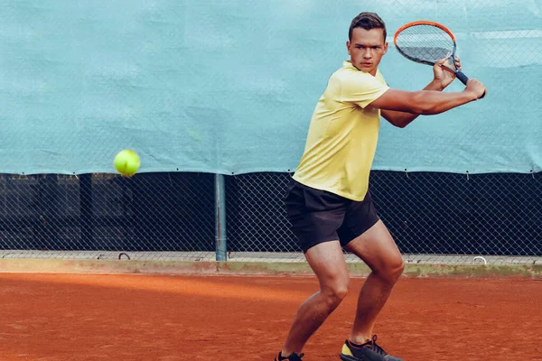 Genç yakışıklı adam tenis kortunda tenis oynuyor. — Stok fotoğraf