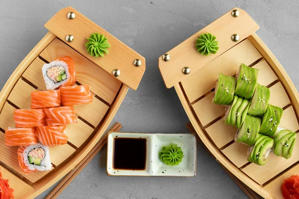 Avocado sushi roll and roll con salmone servito su piatti di legno — Foto Stock