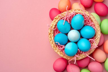 Pembe arka planda dekoratif yuvada boyanmış Paskalya yumurtaları