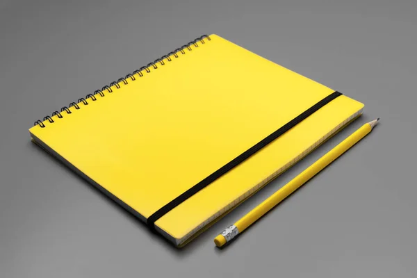 Carnet jaune avec crayon jaune sur fond gris — Photo