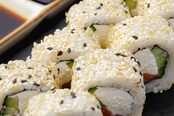 Sushi roll z łososiem, filadelfijskim serem i sezamem na talerzu zbliżenie — Zdjęcie stockowe
