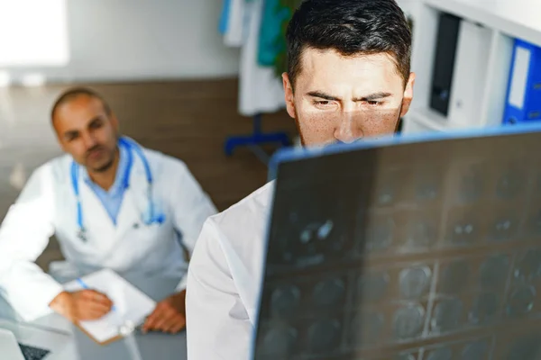 两名男医生检查一名内科病人的MRI脑部扫描 — 图库照片