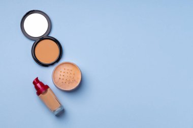 Cilt makyaj ürünleri ve mavi arkaplanda fırça
