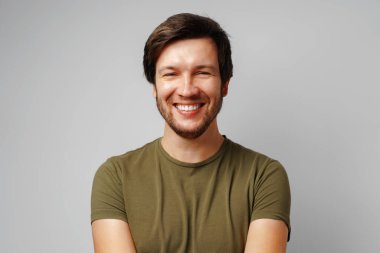 Gri arkaplana gülümseyen yakışıklı genç adam portresi