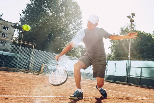 Açık havada tenis oynayan orta yaşlı bir adam dosyalanmış.