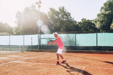 Açık havada tenis oynayan orta yaşlı bir adam dosyalanmış.