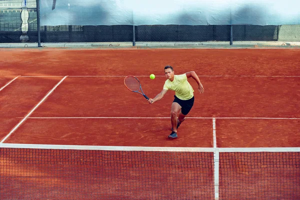 Молодой красивый мужчина играет в теннис на теннисном корте — стоковое фото