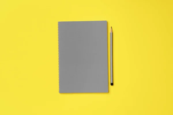 Γκρι σημειωματάριο με μολύβι σε κίτρινο φόντο — Φωτογραφία Αρχείου