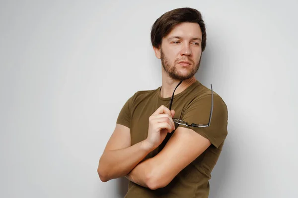 Portrait of a serious pensive young man against grey background — Stock Photo, Image