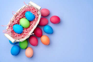 Mavi arka planda dekoratif yuvada renkli Paskalya yumurtaları