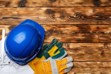 Sert şapka, eldivenler ve bir inşaatçının planları.
