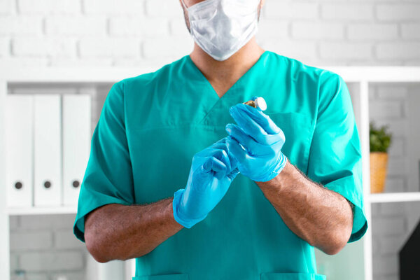 Doctor or nurse in protective medical suit preparing for vaccination