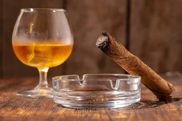 Vaso de whisky y cigarro encendido en un cenicero — Foto de Stock