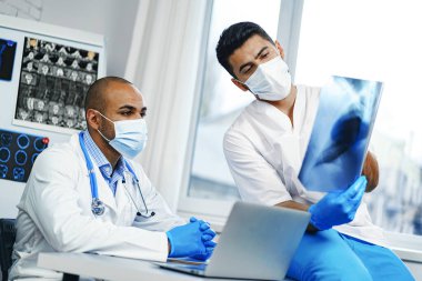 İki erkek doktor, dolaptaki hastanın MRI beyin taramasını inceliyor.