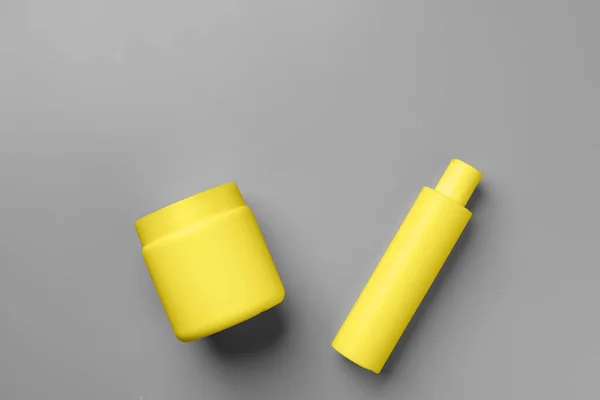 회색 배경 위에 있는 노란색 화장품 용기 — 스톡 사진