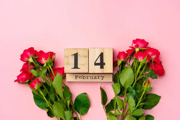 Calendario in legno 14 febbraio e rose su sfondo rosa — Foto Stock