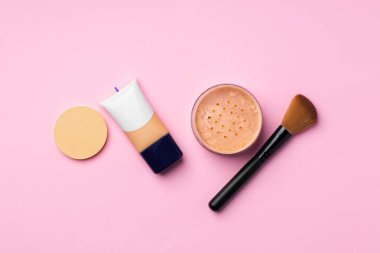 Cilt makyaj ürünleri ve pembe arka planda fırça