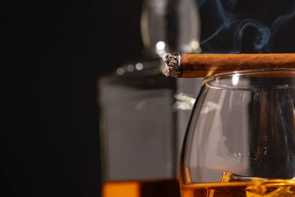 Puros y vasos de whisky quemados sobre fondo negro — Foto de Stock