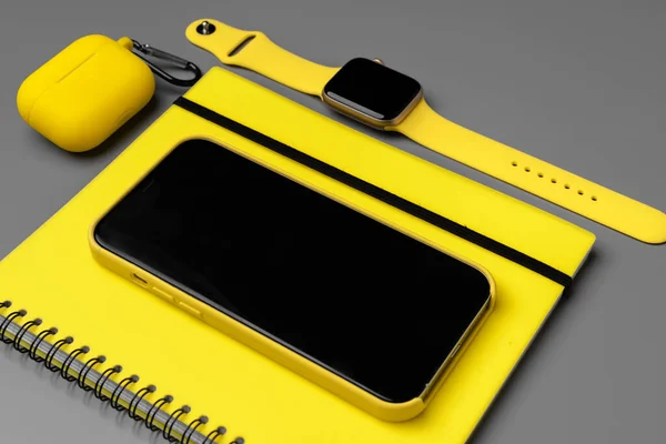 Bloc-notes jaune avec smartphone, smartwatch et écouteurs sur fond gris — Photo