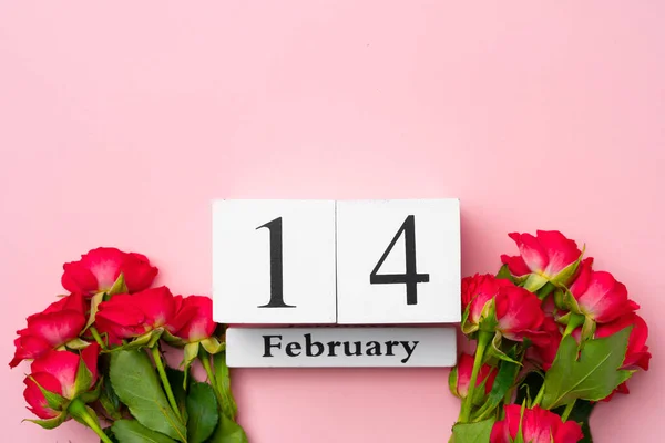 Drewniany kalendarz 14 lutego i róże na różowym tle — Zdjęcie stockowe