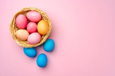 Pembe arka planda dekoratif yuvada boyanmış Paskalya yumurtaları