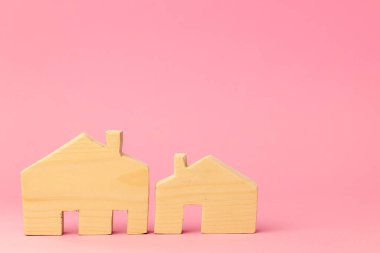 Pembe arka planda ahşap ev minyatürü yakın plan.