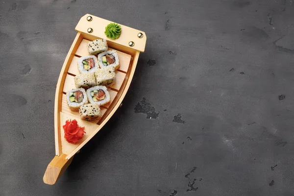 Rotolo di sushi servito su piastra di legno su sfondo nero — Foto Stock